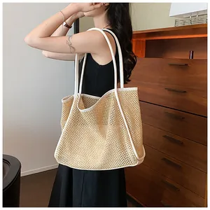 Modisches Model im schwarzen Kleid mit einer großen geflochtenen Strohtasche innen