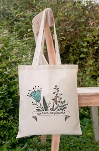 Close-up van de No Rain No Flowers bloemenprint op een katoenen canvas schoudertas