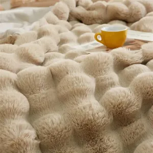 Vue détaillée d'une couverture douce en fausse fourrure de lapin beige à bulles en relief.