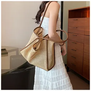 Große gewebte Strandtasche aus Stroh mit braunen Riemen am Model im Wohnzimmer.