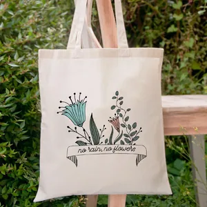 Bloemen canvas draagtas met 'No Rain No Flowers' print in een groene tuinomgeving