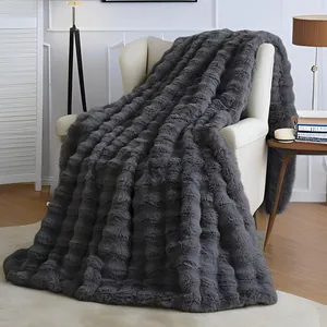 Couverture premium en fausse fourrure de lapin gris foncé avec texture à bulles sur fauteuil.