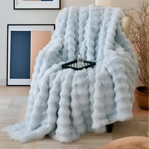 Gros plan d'une couverture douce en fausse fourrure bleue à texture bulles.