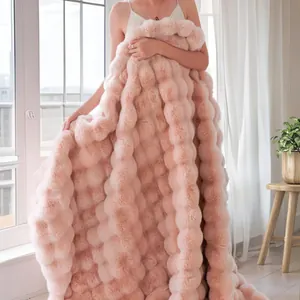 Gros plan sur une couverture rose en fausse fourrure de lapin à texture bulles.