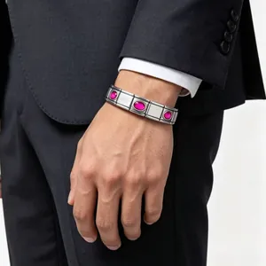 Detailed view of a stainless steel modular charm bracelet with pink oval gemstones on a man's wrist.