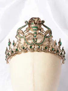 Detailopname van de gouden barokke tiara met een kobra-ontwerp en groene steentjes