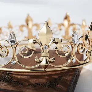 Plano detalle de una corona barroca dorada para hombre con flores de lis y cristales.