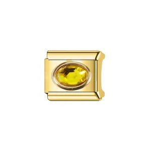 Gros plan d'un charme modulaire en acier inoxydable doré avec une pierre jaune ovale.