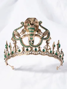 Detail van vintage luxe cobrakroon met groene strass-steentjes en gouden afwerking.