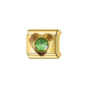 Vue détaillée d'un charm en acier doré en forme de cœur avec un cristal vert éclatant.