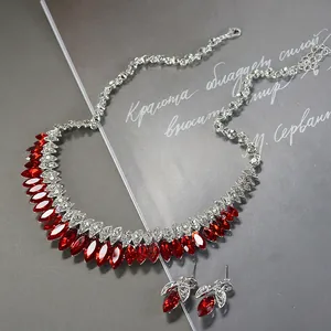 Macro view of a silver-toned bridal jewelry set with red stones and clear crystals.
