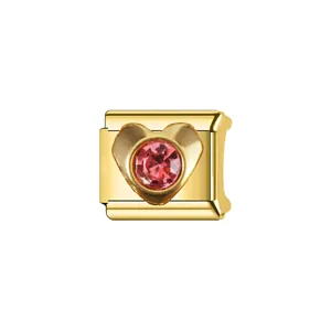 Gros plan d'un maillon de breloque modulaire italienne dorée avec une pierre rose en cœur