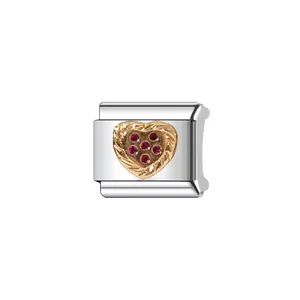 Detailed macro shot of silver modular charm with gold heart and red stone accents