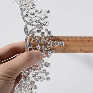 Detailweergave van een zilveren barokke tiara met witte kristallen en een liniaal.