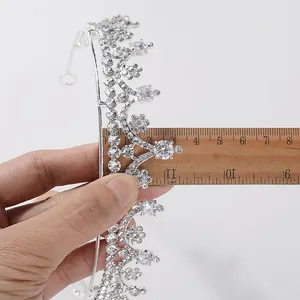 Detail view of silver bridal tiara with rhinestones being measured by a wooden ruler