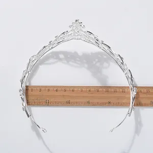 Detailweergave van een zilveren kristallen bruidstiara met een houten liniaal voor schaal