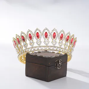 Elegant baroque bridal crown with red teardrop gems displayed on vintage wooden box