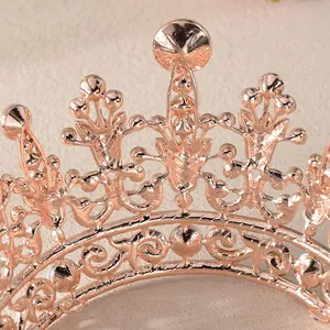 Close-up van barokke patronen op een roségouden kroon met witte strass-steentjes.