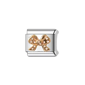 Macro detail of a silver stainless steel Italian charm link with a golden bow pattern