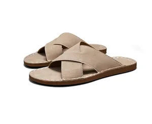 Detailweergave van beige suède herensandalen met kruisbanden en stiksels