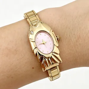 Detailed view of a unique gold-toned fish-shaped watch with a pink dial on wrist