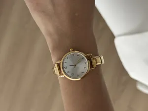 Detail van een elegant goudkleurig dameshorloge met stalen band en zilveren wijzerplaat