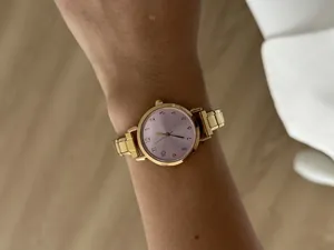 Gedetailleerde weergave van een elegant gouden horloge met roze wijzerplaat