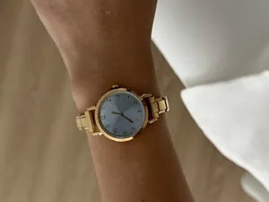 Detailopname van minimalistisch dameskwartshorloge met gouden stalen band om de pols