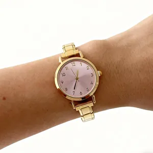 Detailopname van een elegant dameskwartshorloge met gouden stalen band en roze wijzerplaat.
