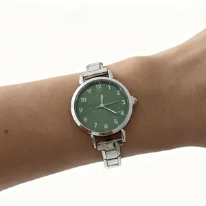 Detailopname van een minimalistisch dameshorloge met groene wijzerplaat en zilveren band