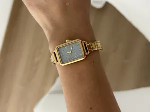 Close-up detail of an elegant gold square quartz watch with a textured grey dial