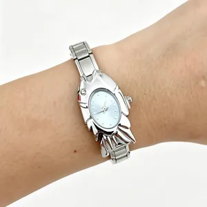 Close-up of a unique fish-shaped silver metal watch with light blue dial worn on a wrist