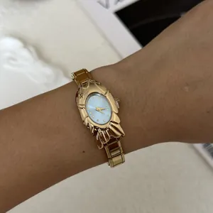 Elegant women's gold watch featuring a unique fish-shaped case and light blue dial.