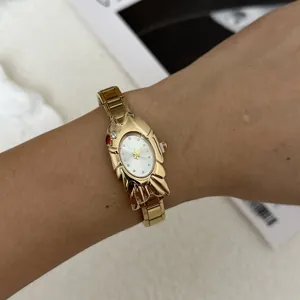 Detailed view of an elegant gold fish-shaped women's watch worn on the wrist