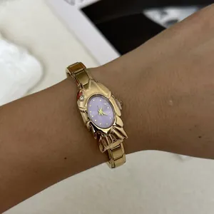 Elegant gold-toned fashion watch featuring a lavender oval dial and unique shell-shaped case