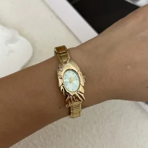 Elegant gold-tone fish-shaped fashion watch with steel band shown on a woman's wrist