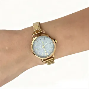 Detailed view of an elegant gold stainless steel modular watch worn on a wrist showing the glitter dial
