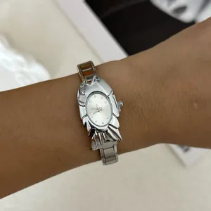 Detailed view of a unique silver fish-shaped fashion watch with a steel strap on a wrist