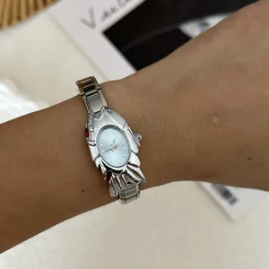 Close-up of a silver fish-shaped fashion watch with a steel band worn on a wrist