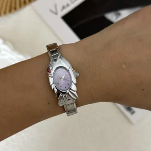 Detailed shot of a silver crab-shaped fashion watch with purple dial worn on wrist.