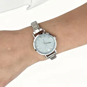 Close-up of a silver stainless steel watch with a shimmering glitter dial on a wrist