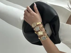 Gros plan de quatre montres carrées dorées élégantes avec lunettes serties sur un poignet
