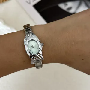Detailed close-up of a unique silver fish-shaped fashion watch worn on a wrist