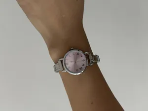 Detailopname van dameskwartshorloge met roze wijzerplaat en modulaire stalen band