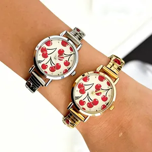 Close-up of stylish women's quartz watches with cherry pattern dials and gold/silver bands.