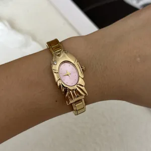 Macro view of unique gold fish-shaped fashion watch with pink dial on a female wrist