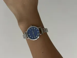 Detail van dameskwartshorloge met blauwe wijzerplaat en modulaire roestvrijstalen band om de pols