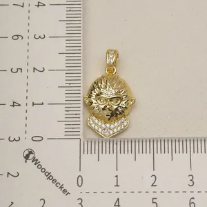 Detailed view of a gold monkey head pendant with crystal accents on a ruler.