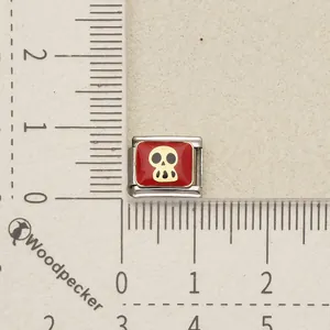 Detailed close-up of a red and gold skull Italian charm link on a measuring scale for DIY bracelets