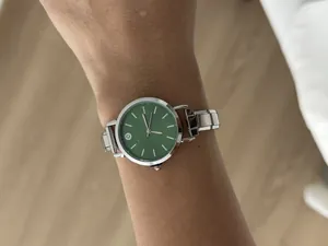 Close-up of a DIY modular stainless steel watch with a forest green dial on a wrist